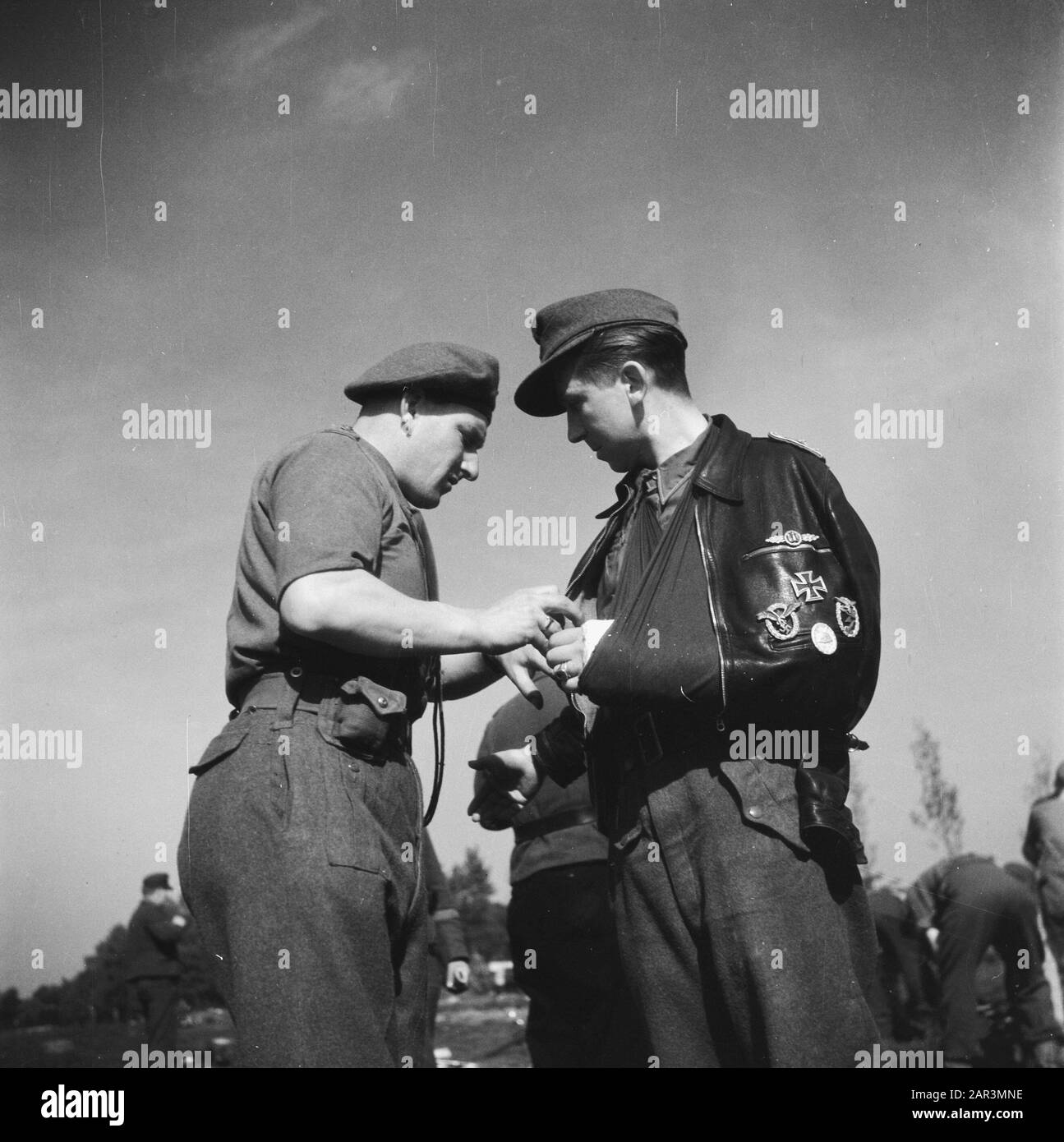 Kapitulation: Soest versandten Waffen durch die Deutschen. Verwundeter deutscher Pilot mit hohen Auszeichnungen wird von britischem Soldaten auf den Abrüstungsfeldern in Soest Anmerkung: Deutsches Luftwaffenmilitär Datum: 10. Mai 1945 Standort: Soest, Utrechter (Provinz) Schlagwörter: Kriegsgefangene, Soldaten, Piloten untersucht Stockfoto