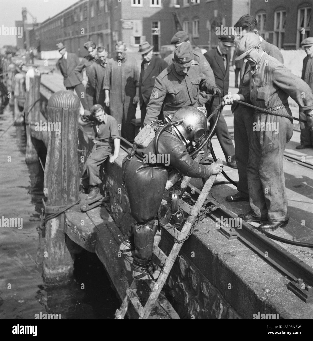 Erholung: Amsterdam Unter der Führung des Kapitäns J. Breman begann die 2. Genie Company in Amsterdam mit Reparaturen von sehr weitreichendem Umfang. Seine Aufgabe ist es, alle Verkehrshindernisse in der Stadt Amsterdam so schnell wie möglich zu beseitigen, einschließlich der Räumung von Bauarbeiten im Hafen. Die Arbeit besteht auch darin, Hindernisse zu beseitigen, die von den Deutschen in den Straßen hergestellt wurden, und die durch Holzblöcke verursachten Gapings im Straßenbelag zu schließen: Das Auspumpen überfluteter Keller etc. EINE ganz besondere Aufgabe ist es, die von den Deutschen geschaffenen Hebekräne an der Javakade zu beleuchten, die tief im Wasser c geblasen wurden Stockfoto