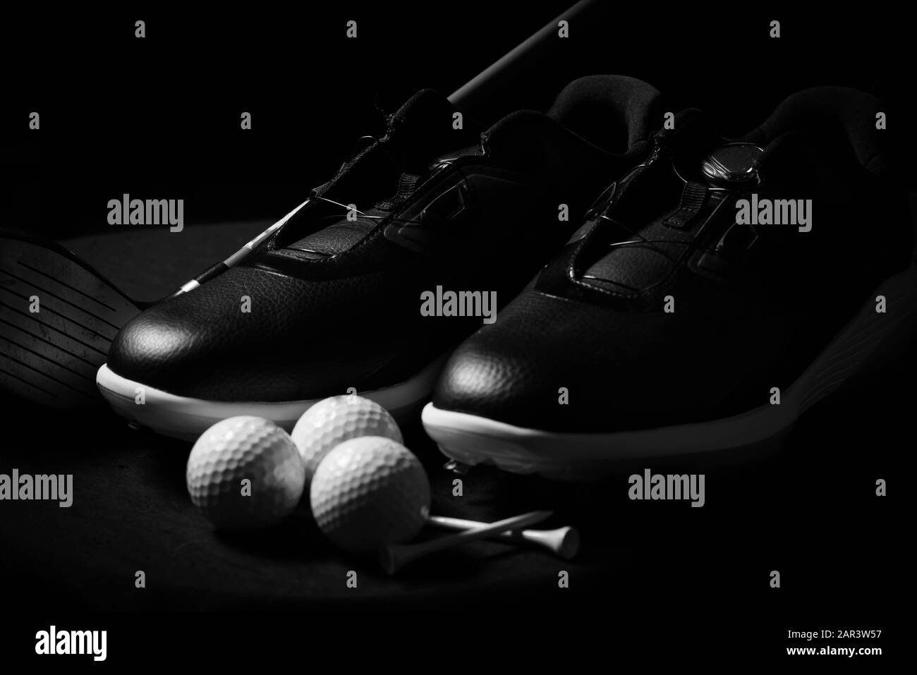 Golfschuhe, Bälle, T-Shirts und Golfclub isoliert auf schwarzem Hintergrund. Stockfoto