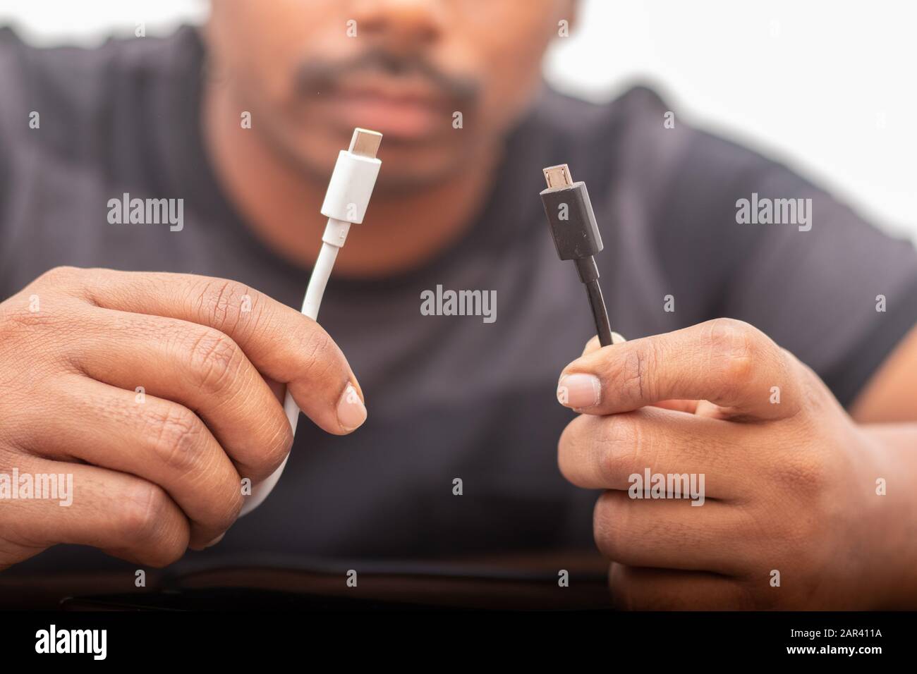 Selektive Fokussierung auf Hände, die Micro-usb- und USB-Anschlüsse des Typs C halten Konzepte, die auf Verwirrung bei den Ladeanschlüssen schließen. Stockfoto