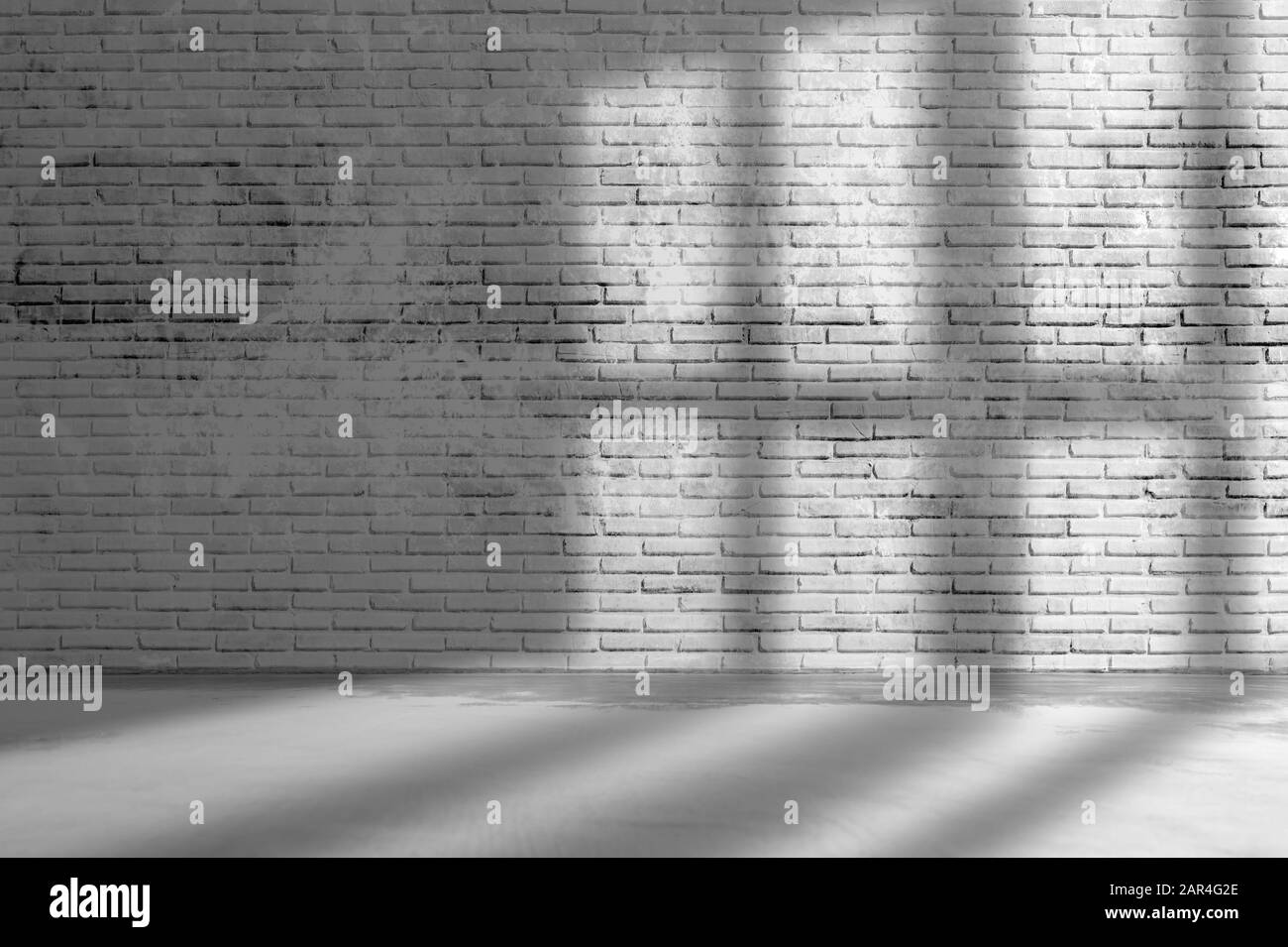 Alte Grunge raue dunkelgraue Mauer aus Backstein mit Fensterschatten und Betonboden. Stockfoto