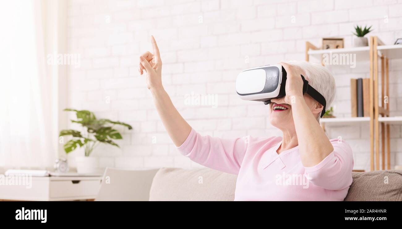 Fröhliche Seniorin genießt zu Hause moderne Technologien Stockfoto