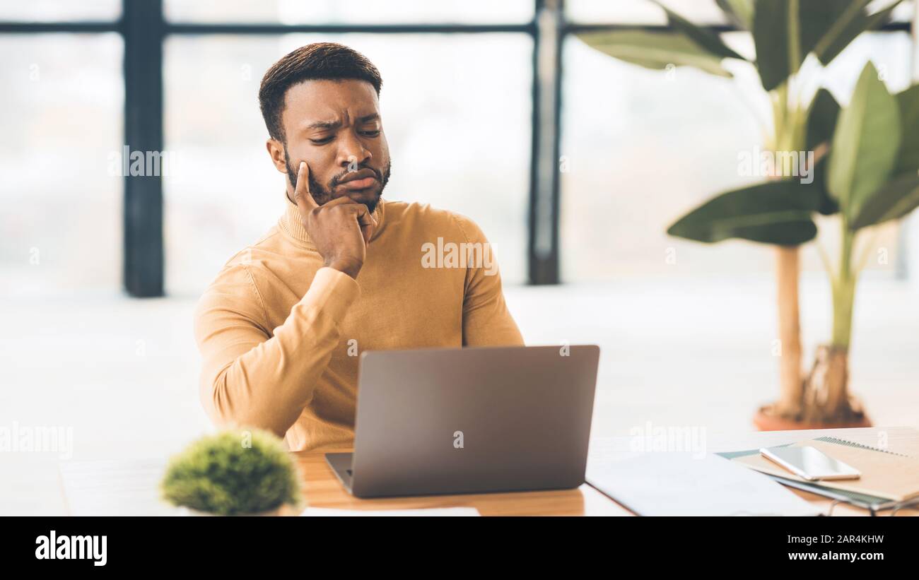 Fokussierter schwarzer Mann, der im Büro mit einem Laptop arbeitet Stockfoto