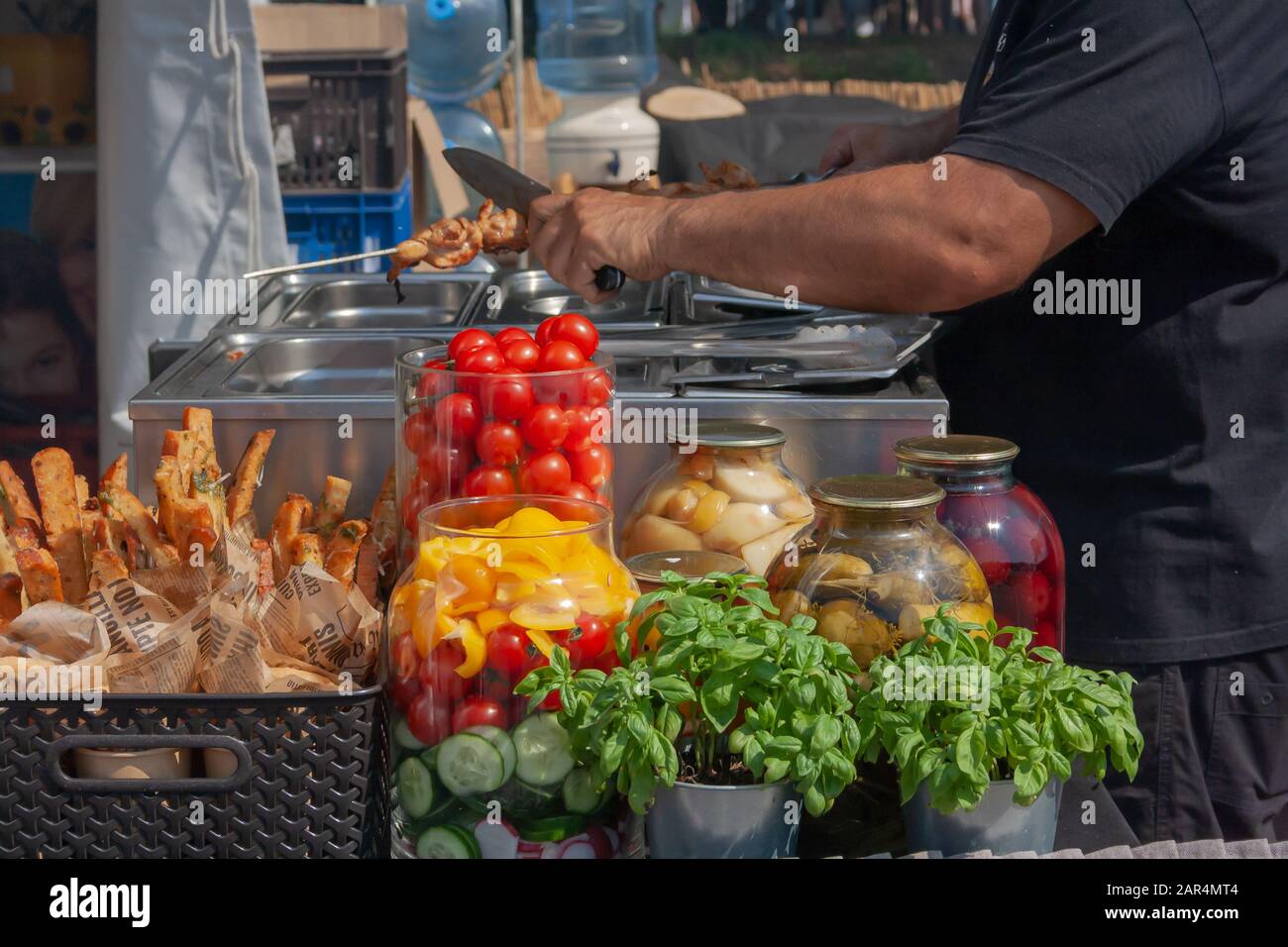 Ein Mann verkauft frisches Gemüse der Saison. Tomaten und Basilikum im Hintergrund Stockfoto