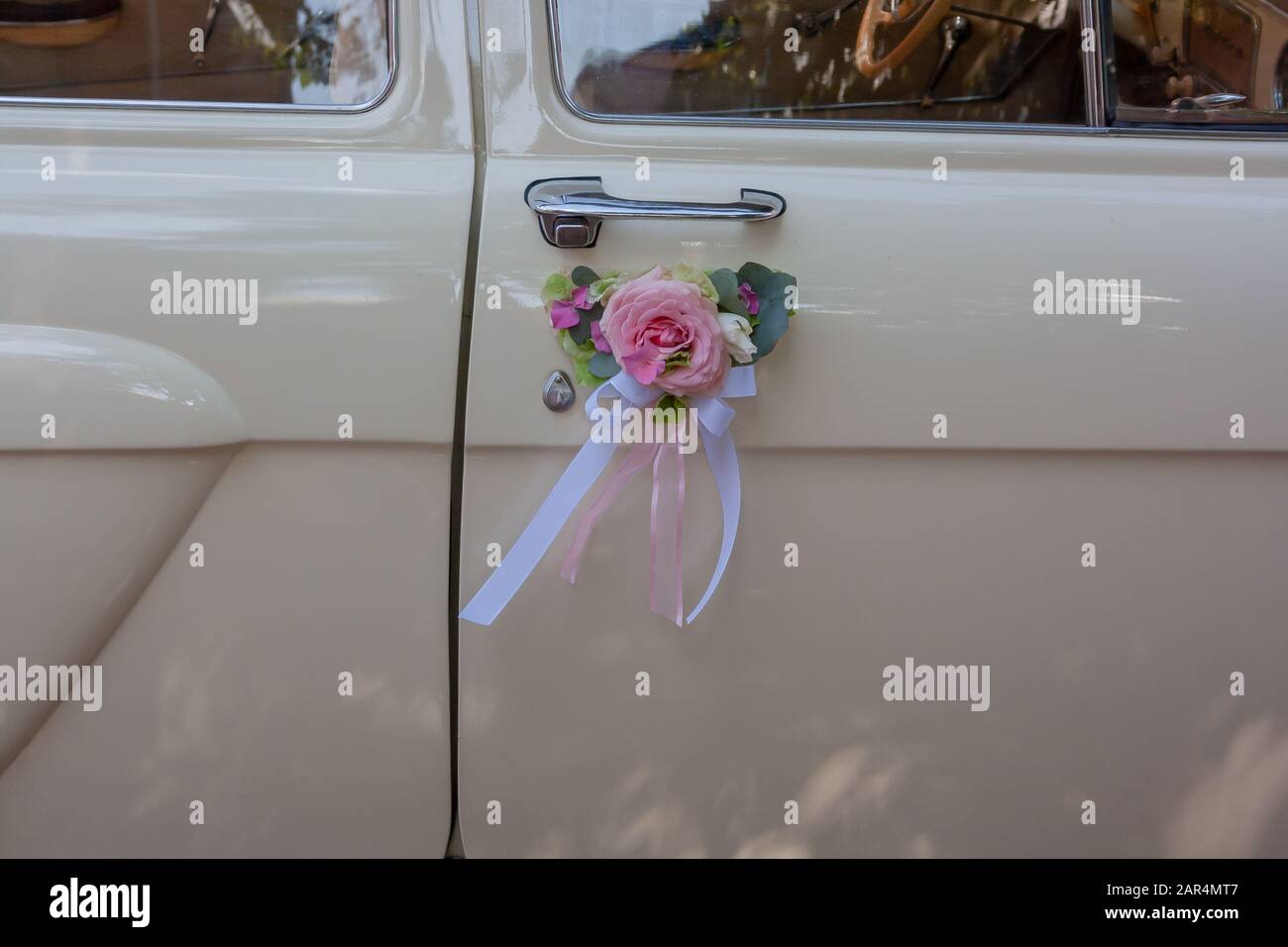 Hochzeitsauto mit schönen Dekorationen aus pinkfarbenen und orangefarbenen Rosen Stockfoto