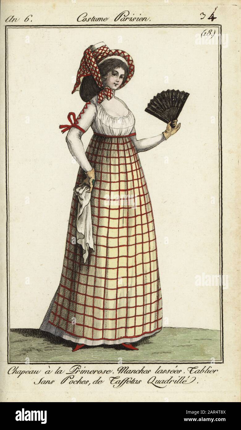 Frau in der Mode von 1798. Sie trägt einen Hut im Primerose-Stil, der mit einem karierten Fichu verbunden ist. Ihr Kleid hat geschnürte Ärmel, und ihre taffetafarbige Schürze ohne Tasche ist in Schach. Sie hat einen Fan und einen Kerchef. Der Hut ist möglicherweise von der Tracht eines provenzalischen Bauern inspiriert, der von Madame St. Aubin in Nicolas Dalayracs Oper Primerose gespielt wurde, die im Jahr 2008 debütierte. Chapeau a la primerose. Manches Lassees. Tablier sans poches de taffetas Quadratille. Handfarbige Kupferstichgravur von Pierre de la Mesangere's Journal des Modes et Dames, Paris, 1798. Die Illustrationen in Band 1 stammen von Carle Vernet, Claude Louis Stockfoto