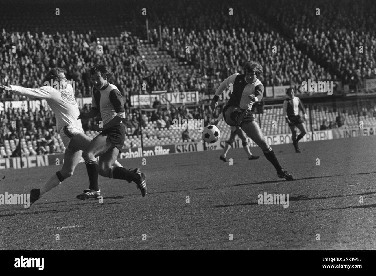 Feyenoord / NEC: 2-0 Feyenoordspeler De Jong schießt auf das NEC-Ziel, flankiert von den NEC-Spielern Gerritsen und Feyenoordspeler Van Deinsen Datum: 27. Februar 1977 Ort: Rotterdam, Zuid-Holland Schlüsselwörter: Sport, Fußball, Fußballer persönlicher Name: Deinsen, Jan van, Gerritsen, Ben, Jong, Theo de Stockfoto