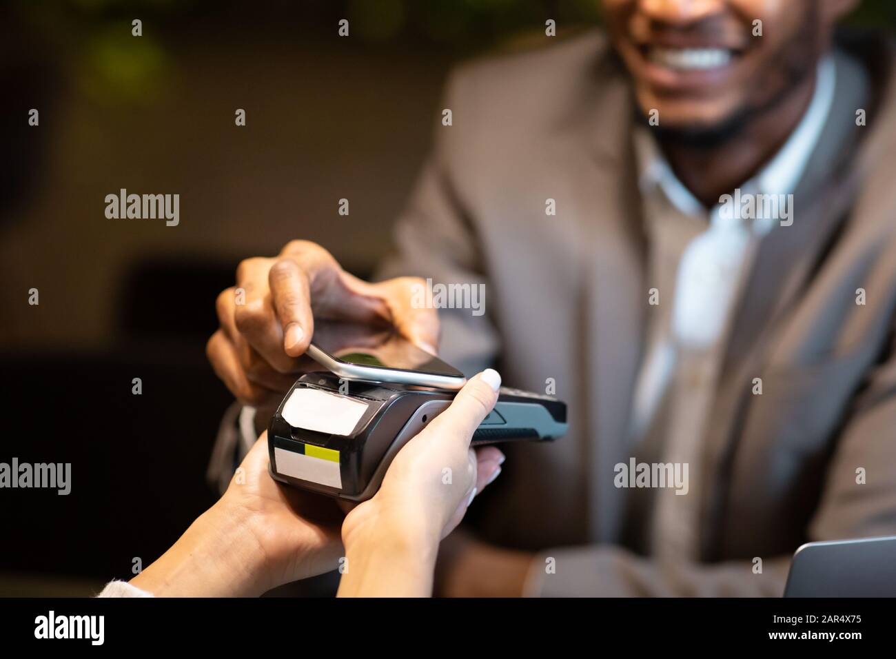 Afro-Geschäftsmann zahlt mit Handy an der Bar Stockfoto