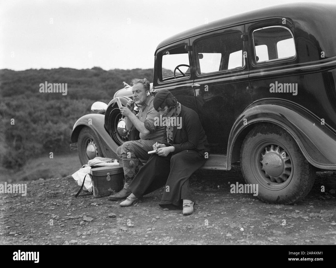 Island Willem van de Poll und die deutsche Journalistin Anita Joachim auf dem Fußbrett des Autos, mit dem sie eine Reise machen. Während die ersten Schaves, macht die anderen Notizen Datum: 1934 Ort: Island Schlüsselwörter: Autos, Journalisten, Schreiben persönlicher Name: Joachim, Anita, Poll, William of the Stockfoto