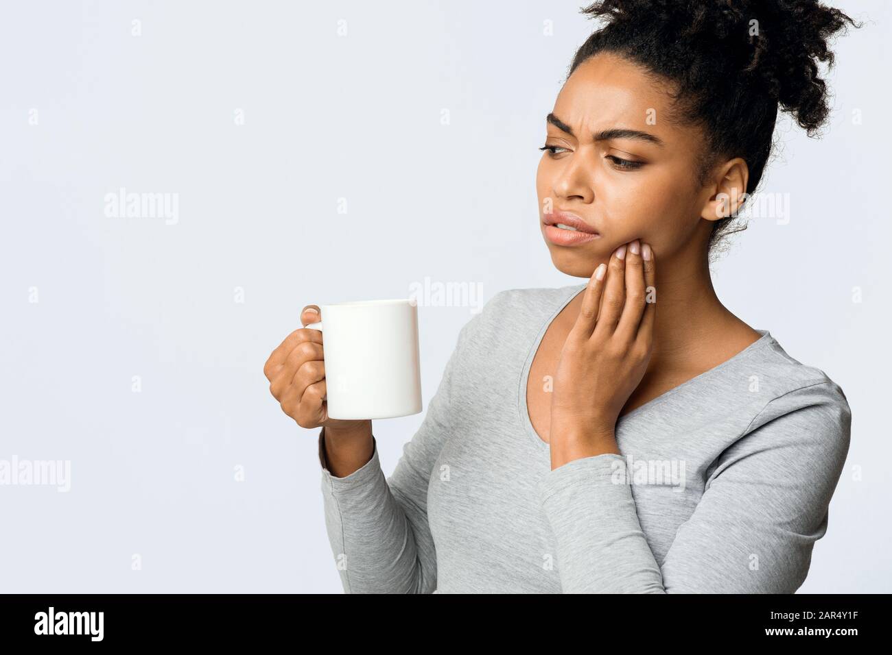 Afro Mädchen, das mit empfindlichen Zähnen leidet und heißen Tee trinkt Stockfoto