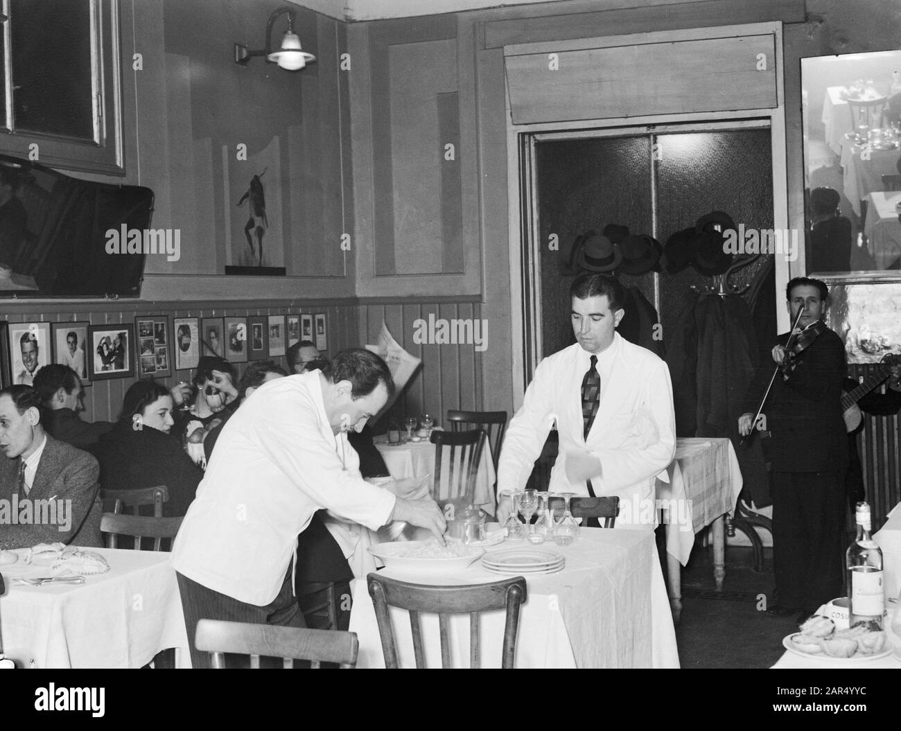 ROM: Besuch der Stadtgäste am Tisch im Restaurant von Alfredo, König der Spaghetti, während Alfredo Spaghetti serviert. Hintergrund ein Geiger Datum: 10. Januar 1938 Ort: Italien, Rom Schlüsselwörter: Mahlzeiten, Musiker, Restaurants Stockfoto