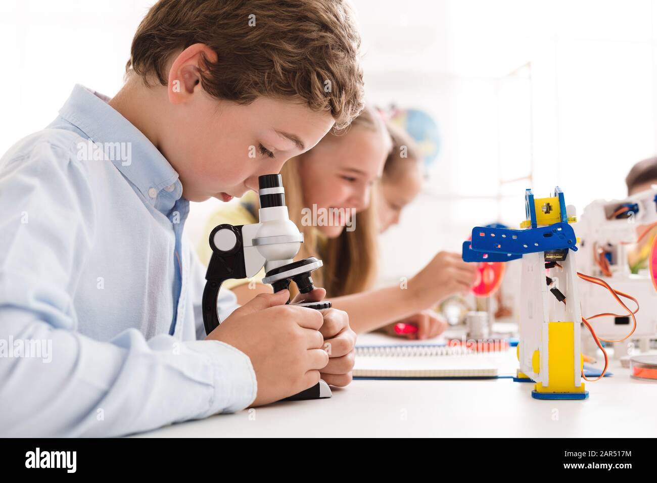 Smart Boy mit Blick auf das Mikroskop in der Klasse "Stem Education" Stockfoto