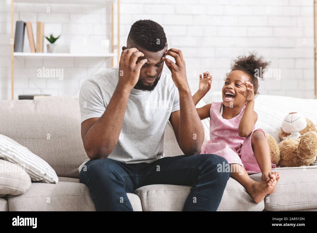 Schwarzer Vater, der den Kopf hält, müde von einer schlechten Tochter Stockfoto