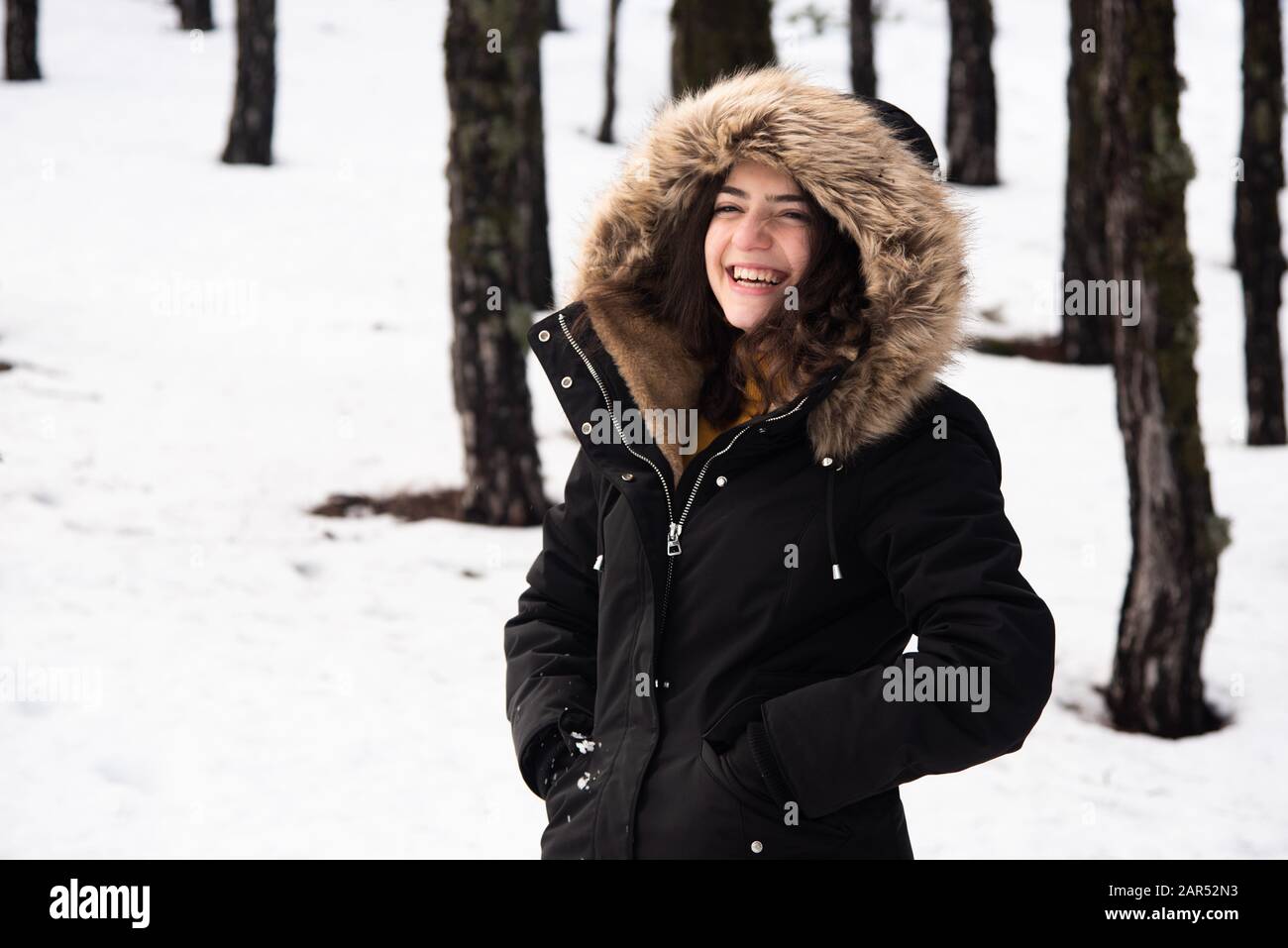 Junges glückliches und wunderschönes Mädchen im Teenager-Alter, das sich in Winterkleidung kleidete und auf Schnee stand und lächelte. Troodos Berge auf Zypern Stockfoto