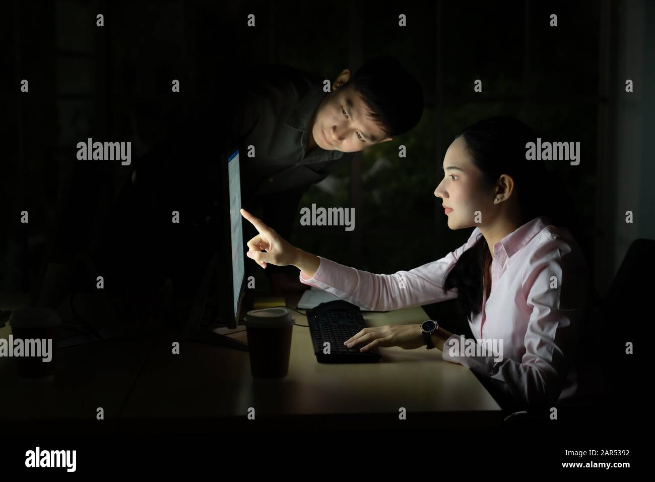 Junge Erwachsene asiatische Unternehmer diskutieren mit Kollegen über die Arbeit spät in der Nacht in ihrem Büro mit Computer. Mit so hart arbeiten und arbeiten l Stockfoto
