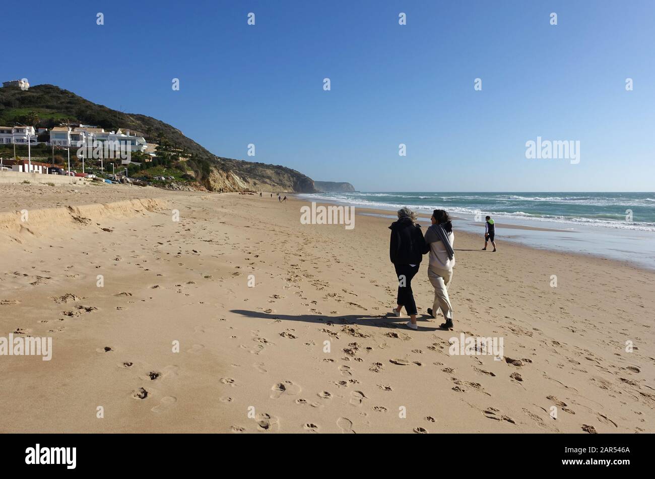 Salema, Portugal 29. Dezember 2019: Menschen, die am Strand in der Küstenstadt Salema in Portugal spazieren; Stockfoto