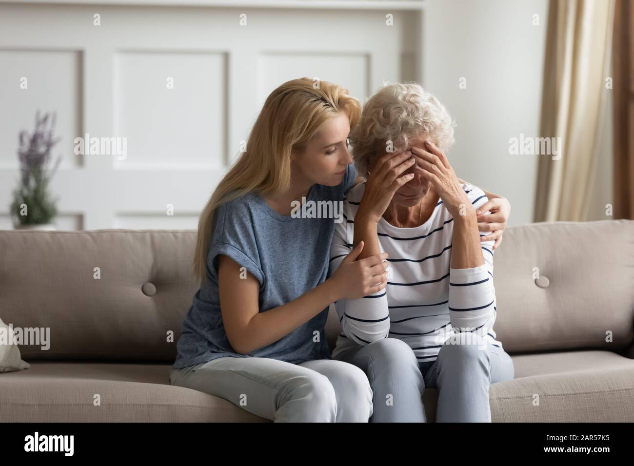 Besorgniserregende blonde junge Frau beruhigt frustrierte Mutter mittleren Alters. Stockfoto