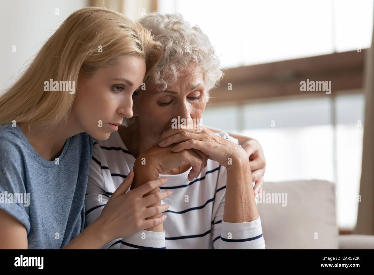 Empathische Tochter, die verzweifelte Mutter mittleren Alters umarmte. Stockfoto