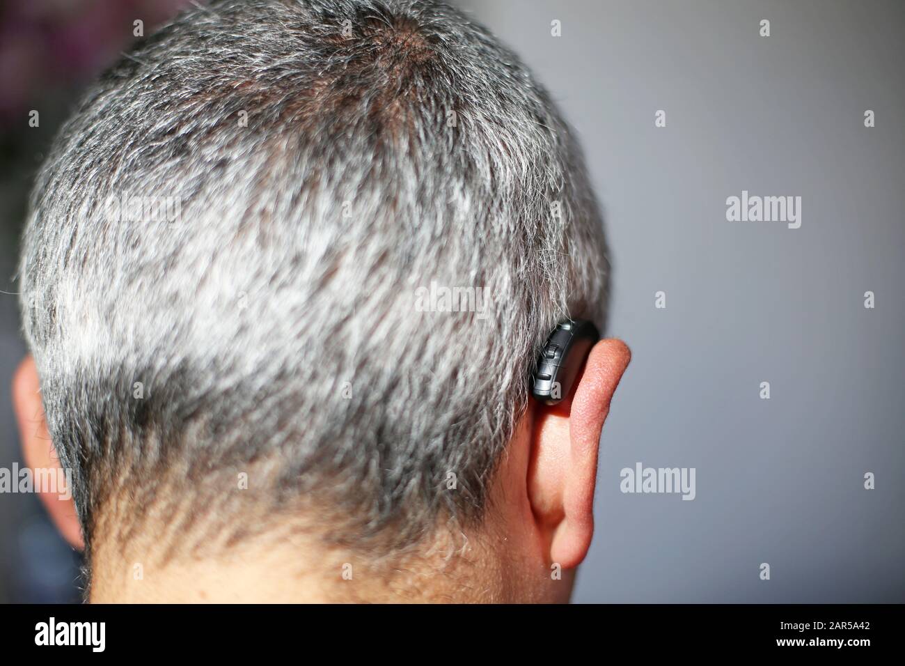 Hörgerät hinter dem Ohr eines grauhaarigen Mannes Stockfoto