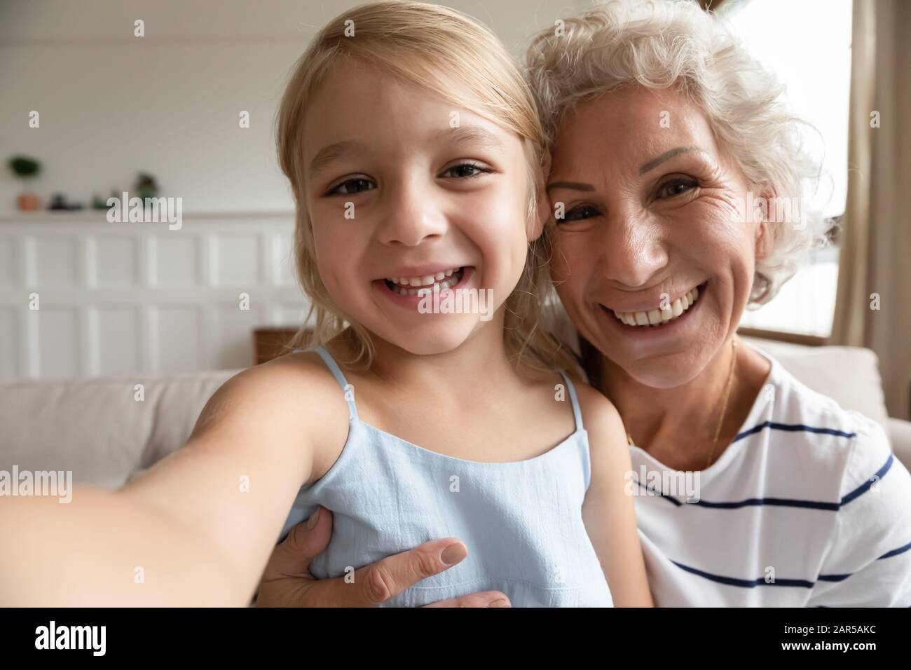 Kleine Vorschul-Enkelin, die lustige Videos mit aufgeregter älterer Großmutter aufzeichnet. Stockfoto