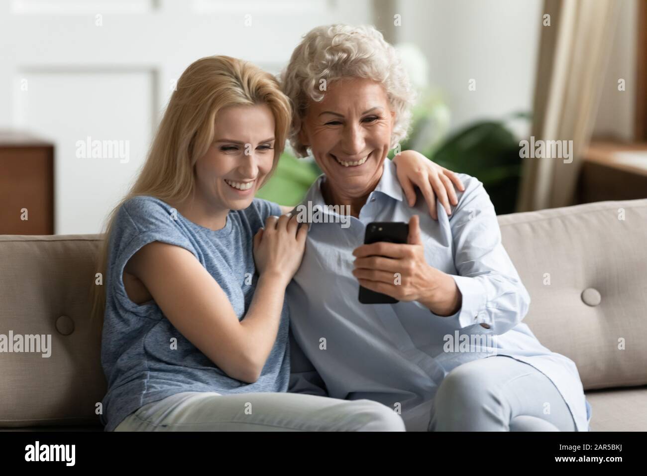 Lächelnde junge Dame umarmt glückliche ältere Mutter, posiert für selfie. Stockfoto