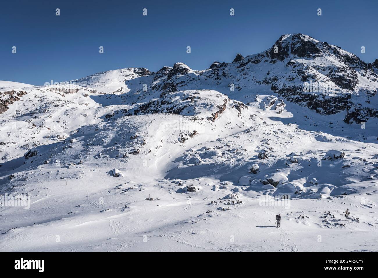 Wanderer allein im Winterberg, vor hohen Gipfeln Stockfoto