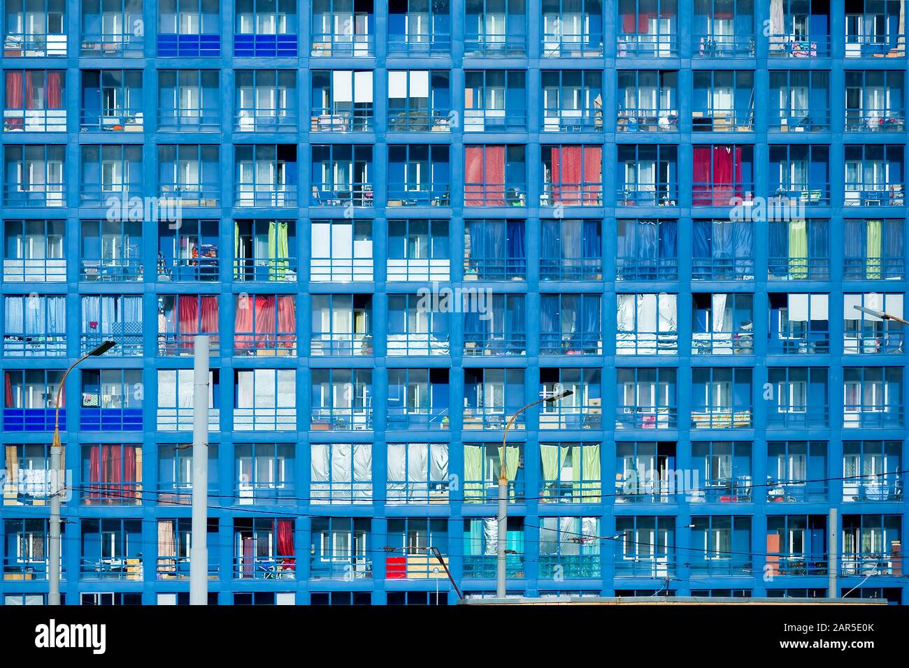 Mehrfaches Foto des mehrstöckigen Gebäudefragments, das den blauen Himmel reflektiert. Strukturelle Glaswand mit kurvenförmigen Formen. Moderne Architektur Stockfoto