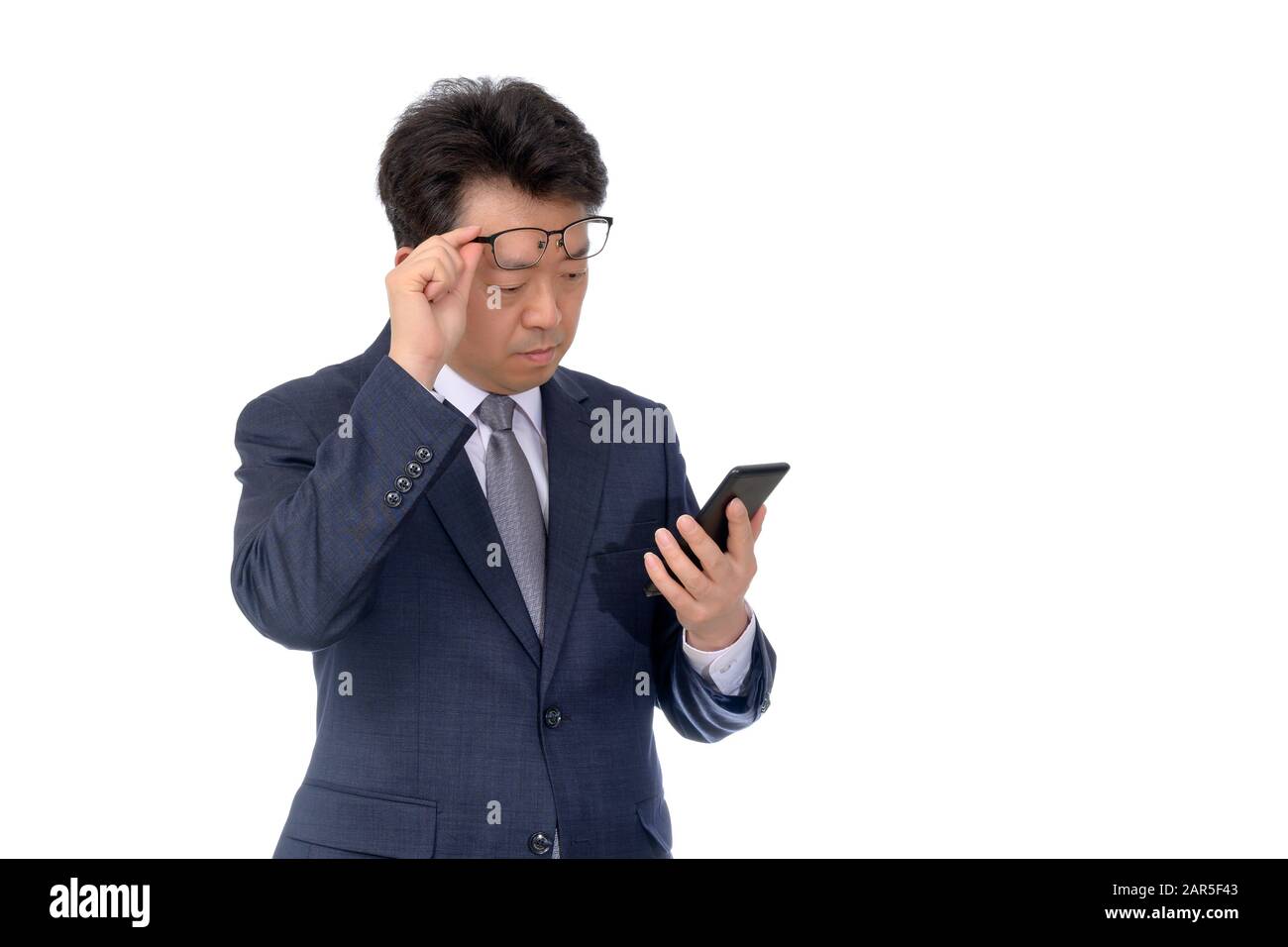 Asiatischer Geschäftsmann versucht, etwas auf seinem Handy zu lesen, schlechte Sicht, Presbyopie, Myopie. Stockfoto