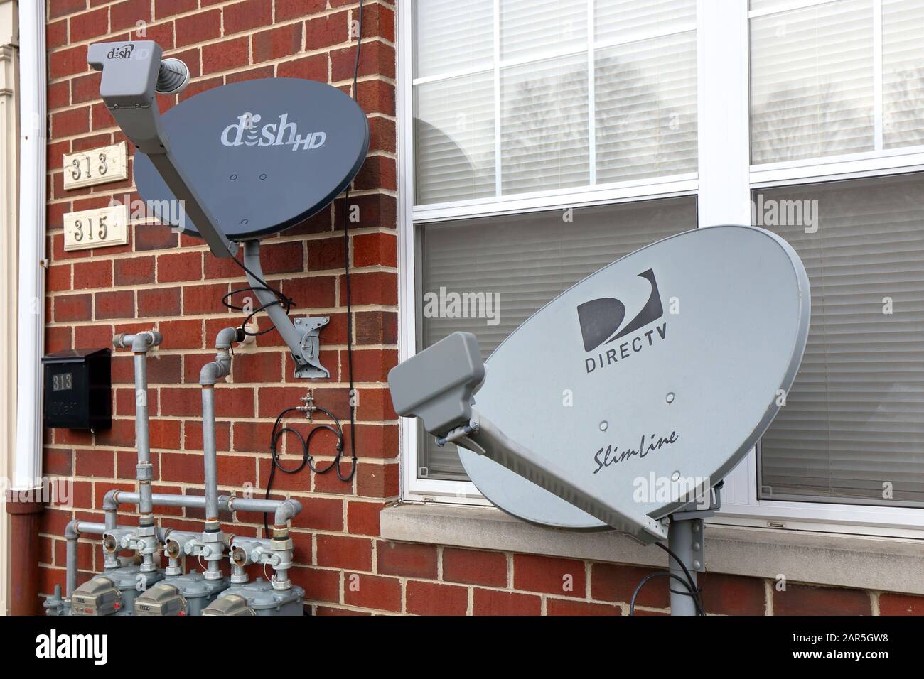 Ein Paar Satellitenschüssel-TV-Empfänger, ein Geschirrnetz, das andere DirecTV Stockfoto