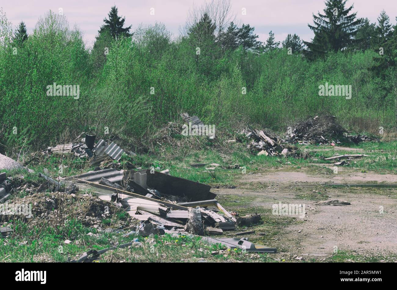 Viele Müllhaufen infolge menschlicher Aktivität in der Nähe des Frühlingsgrünwaldes Stockfoto