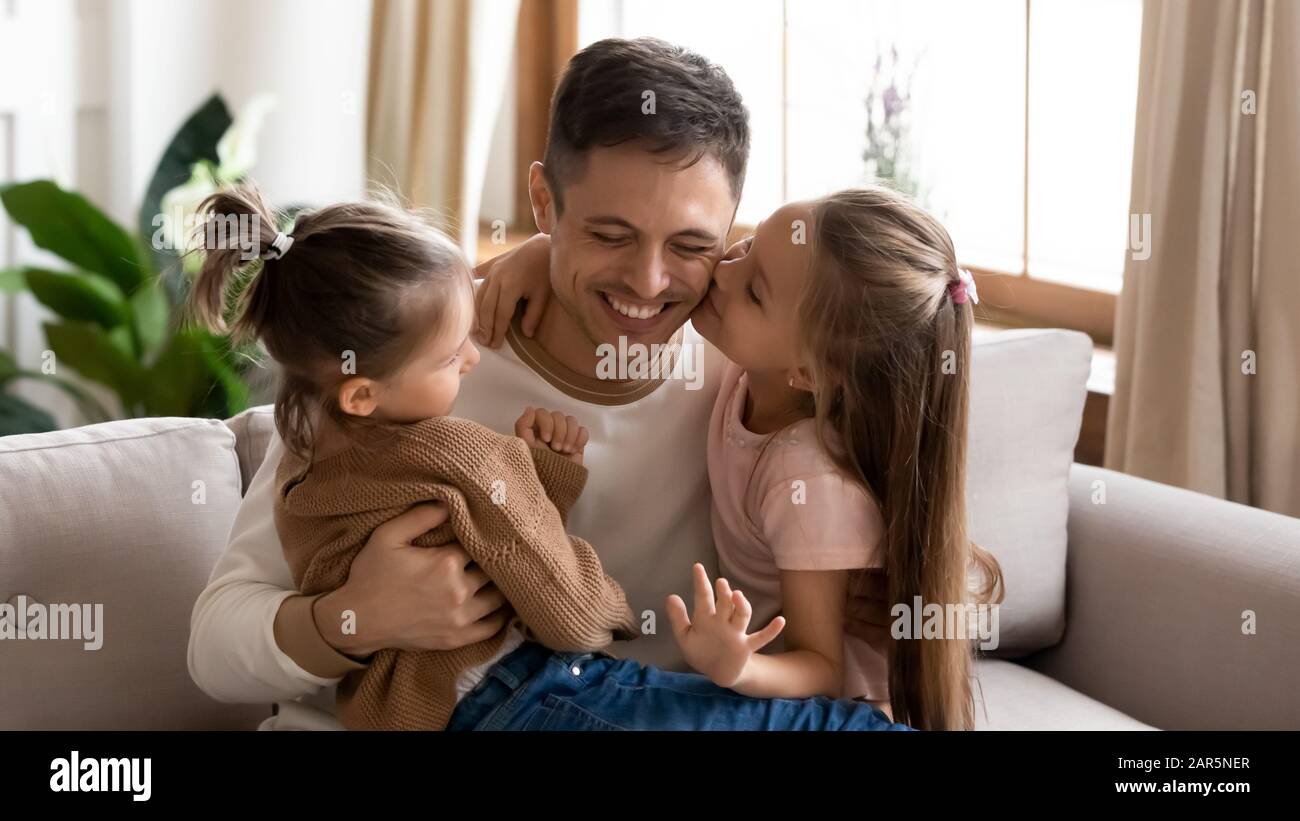Fröhlicher junger Papa Kuscheltier entspannen Sie sich mit kleinen Töchtern zu Hause Stockfoto