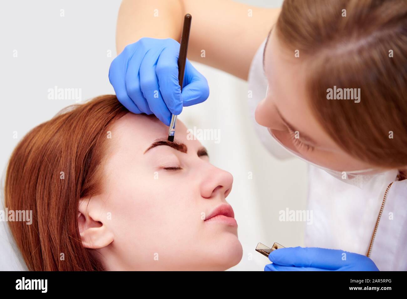 Junge Frau auf Augenbrauenkorrektur in der Klinik für Kosmetologie. Stockfoto