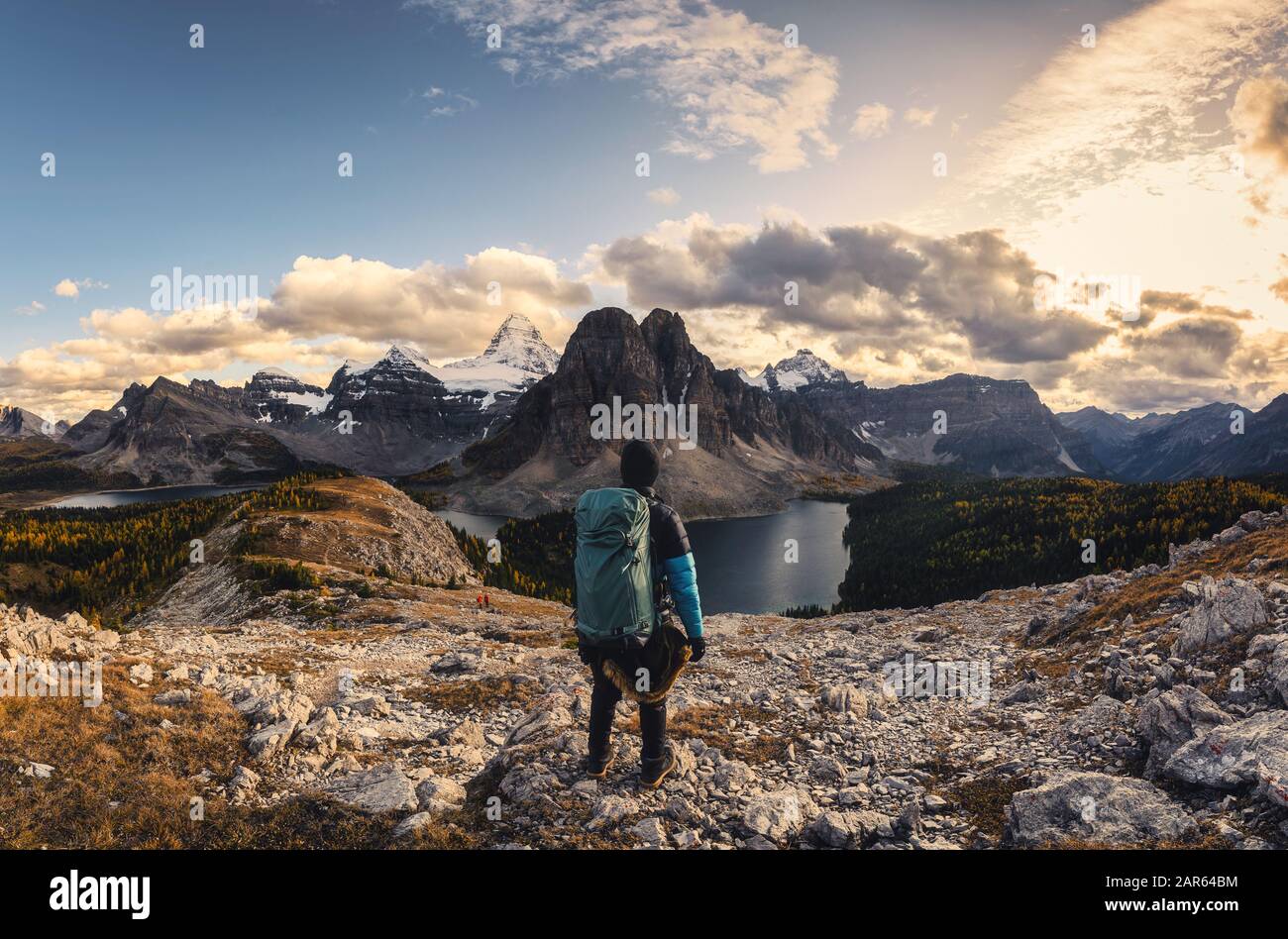Panorama-Mann-Reisende, die auf der Spitze von Nublet mit felsigen Bergen und See im Assiniboine Provinzpark in Alberta, Kanada, stehen Stockfoto