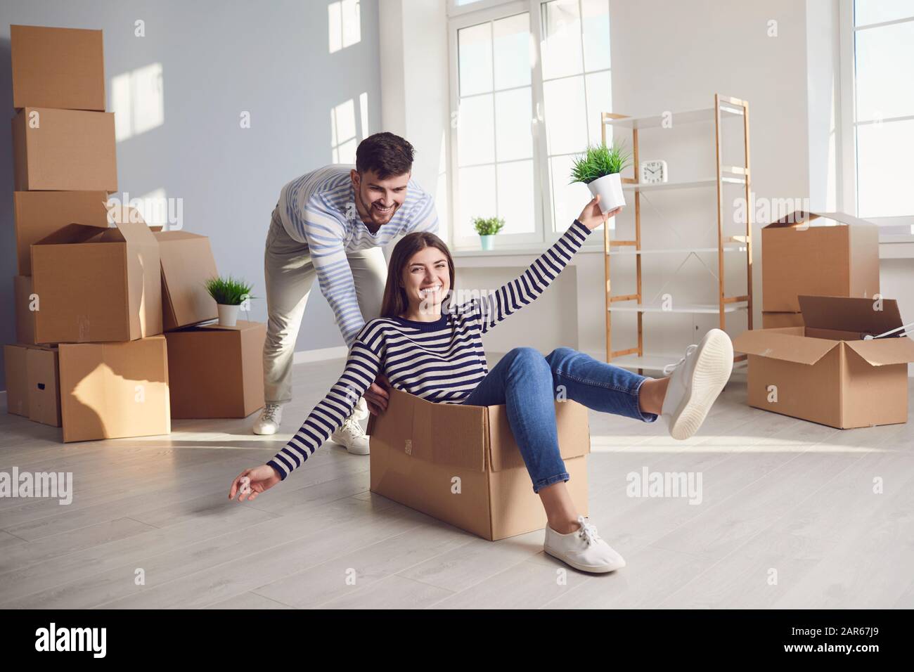Ein fröhliches Paar spielt mit einem beweglichen Kasten in einem hellen Raum eines neuen Hauses. Stockfoto