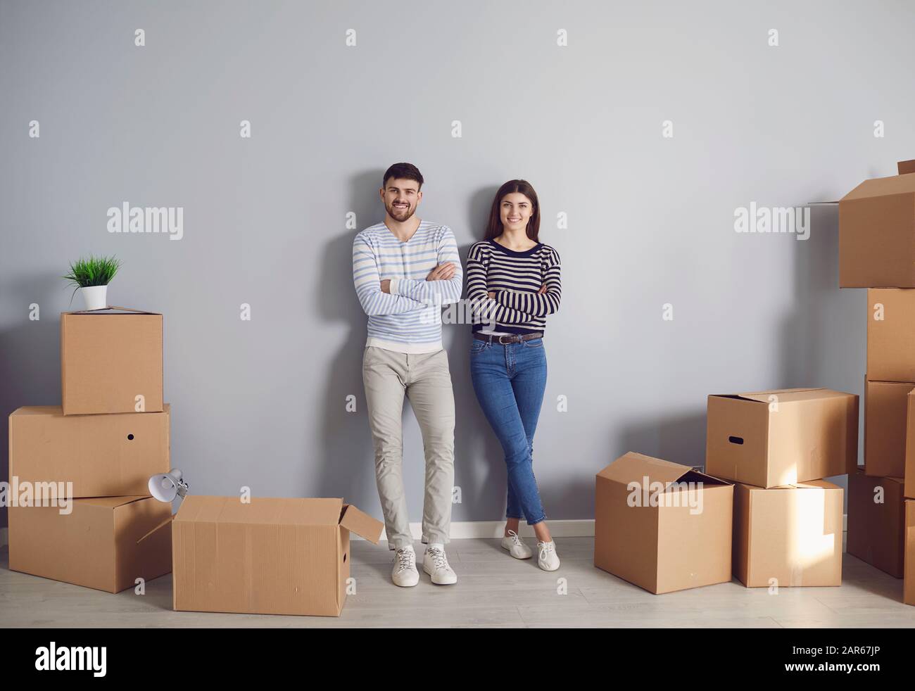 Junge Paar-Familie mit Kisten, die in einem neuen Hausraum umziehen sollen. Stockfoto