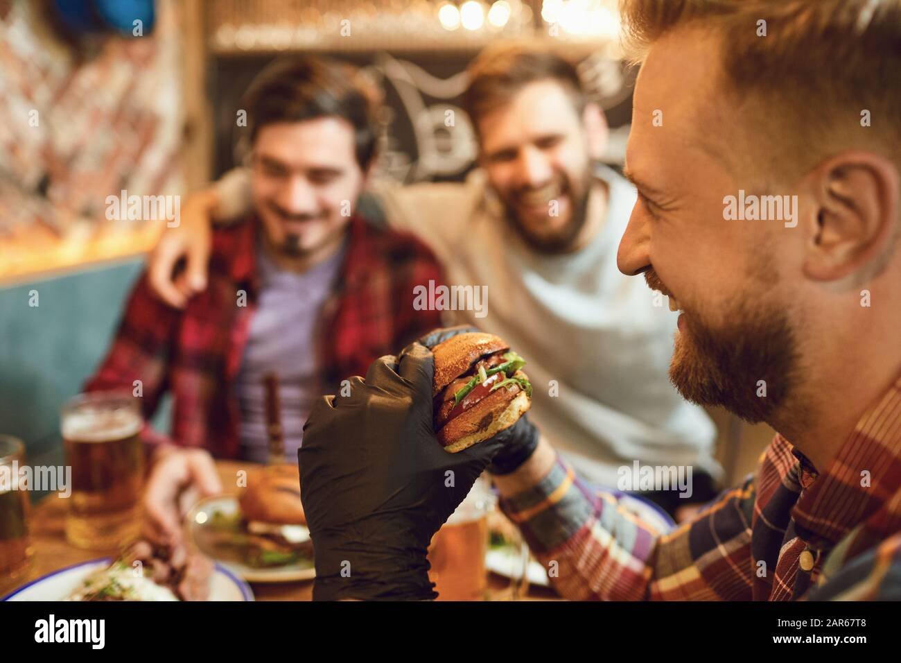 Ein Mann isst einen Burger in einem Café in der Kneipenbar. Stockfoto