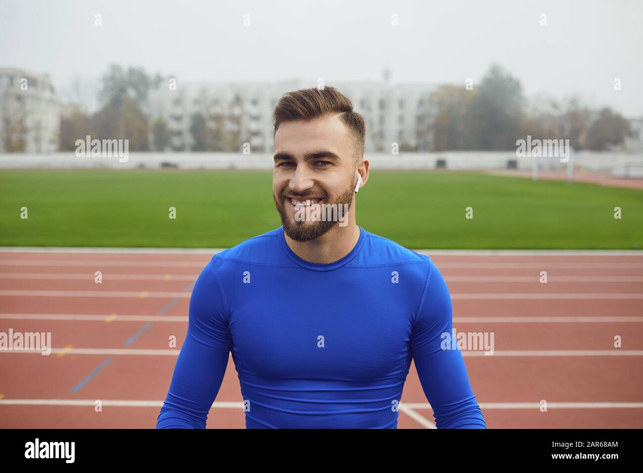 Sport Kerl in blauer Kleidung lächelt, während im Stadion im Nebel auf der Suche Stockfoto