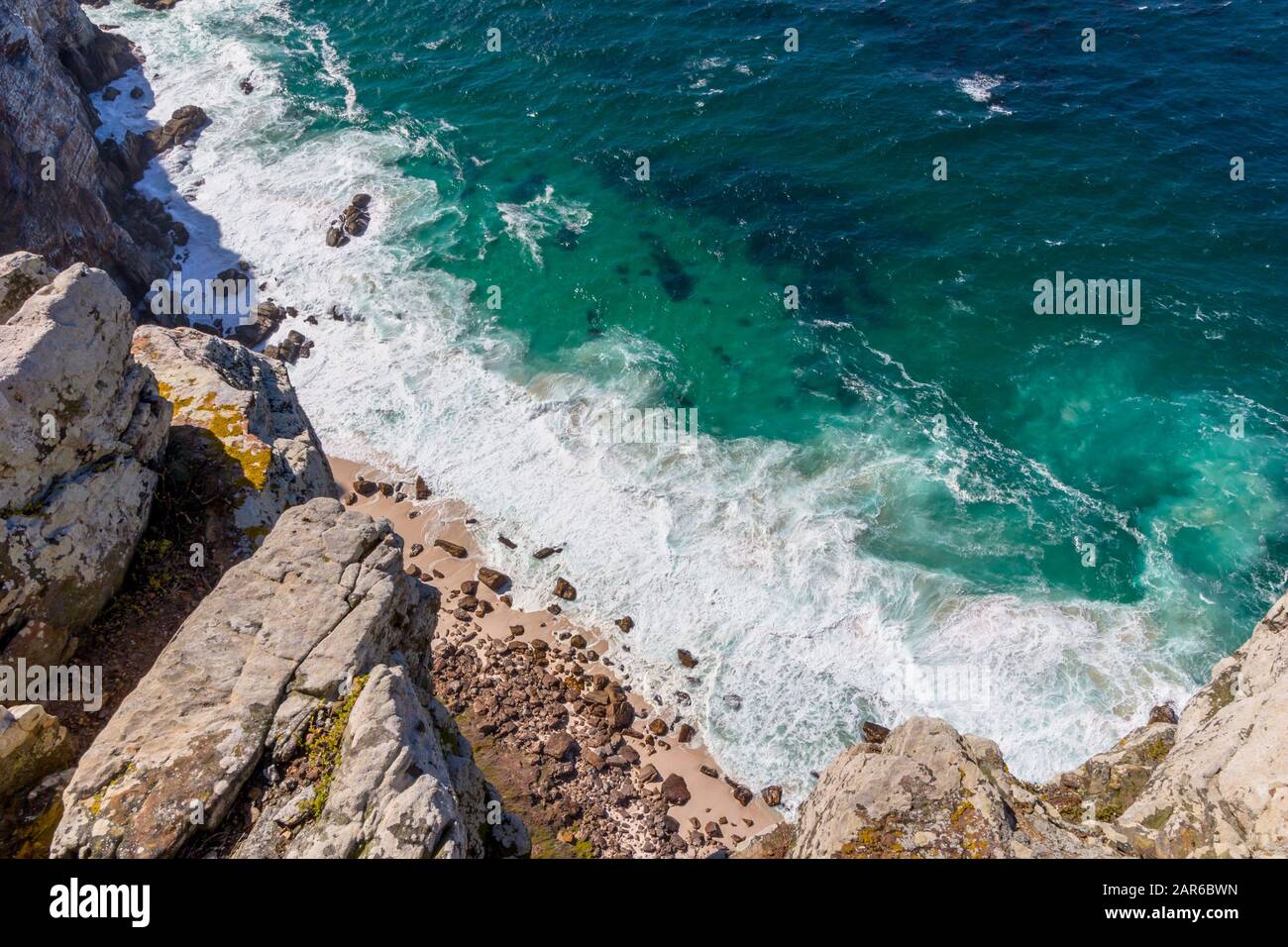 Blick über die Klippen am tiefen Ozean und Wellen, die am kleinen Strand und an den Felsen am Cape Point in der Nähe von Kapstadt Südafrika wirbeln Stockfoto