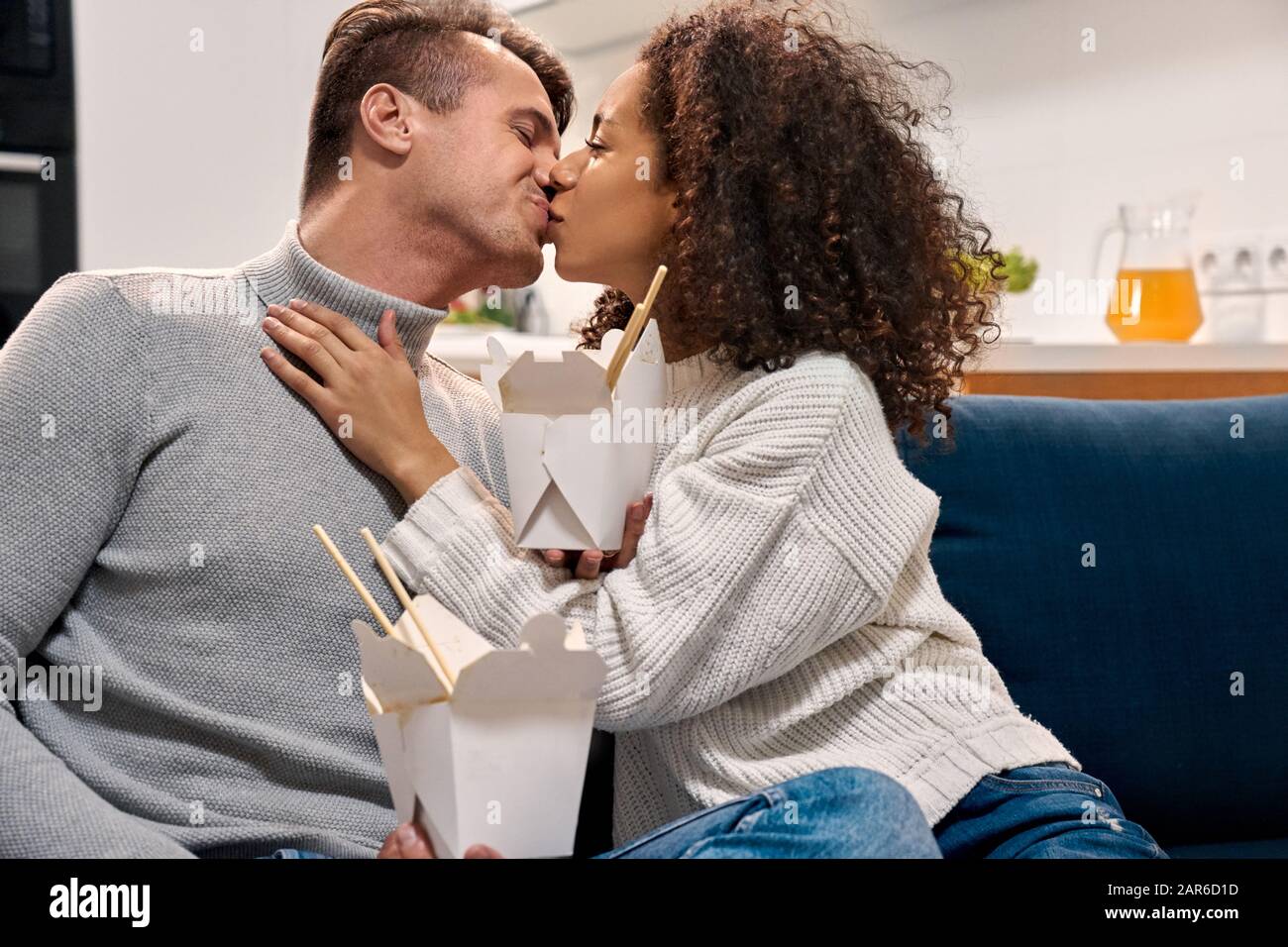 Junger Erwachsener und afroamerikanische Frau, die zu Hause küssen Stockfoto