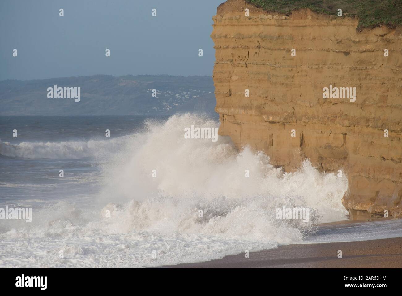 Hohe weiße Brecher von einem Kanal stürmen den Strand und die Sandsteinfelsen am Hive Beach, in der Nähe von West Bay, Dorset, Januar Stockfoto