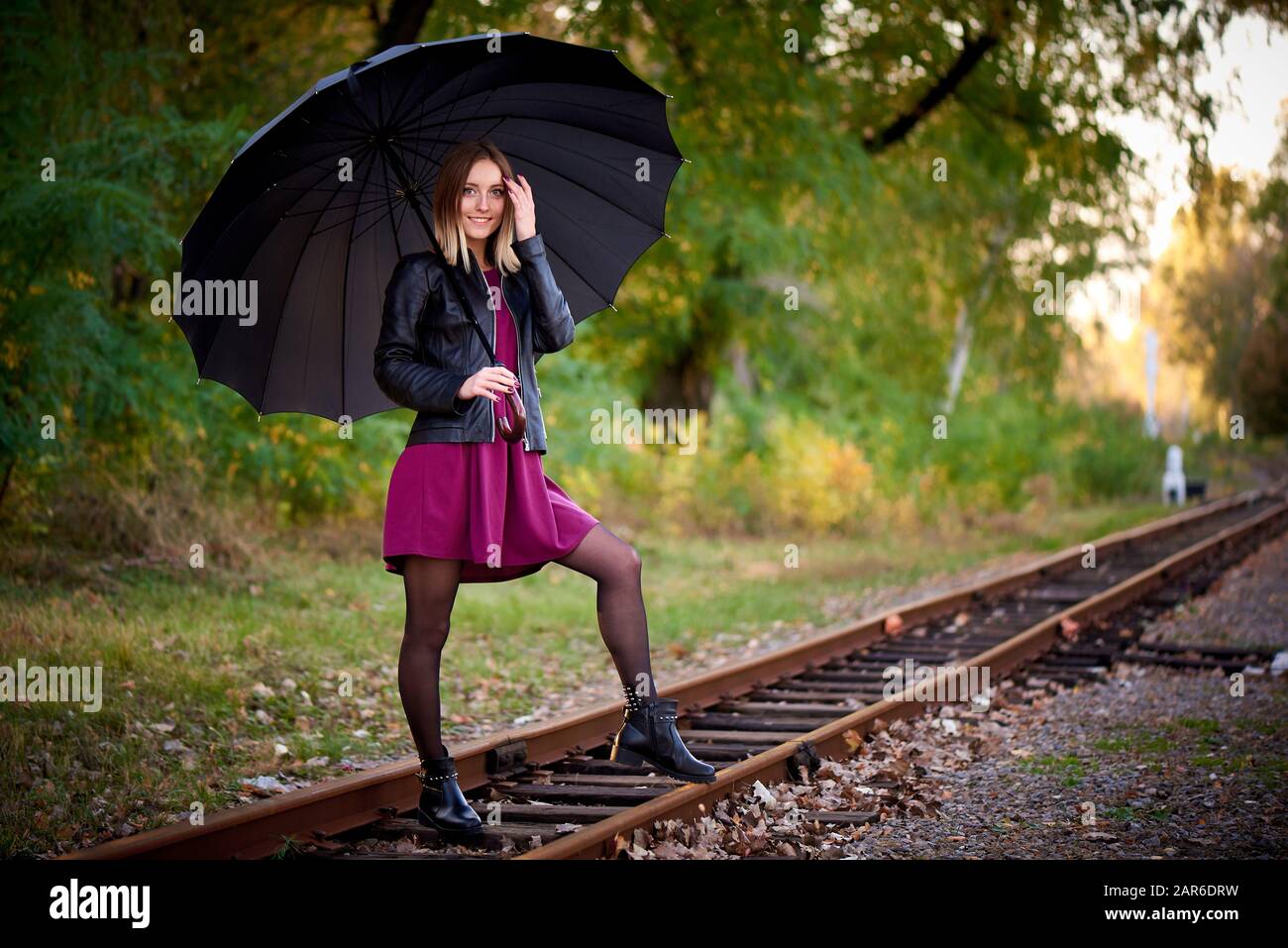 Ein Mädchen mit schwarzem Regenschirm auf der Bahn. Stockfoto