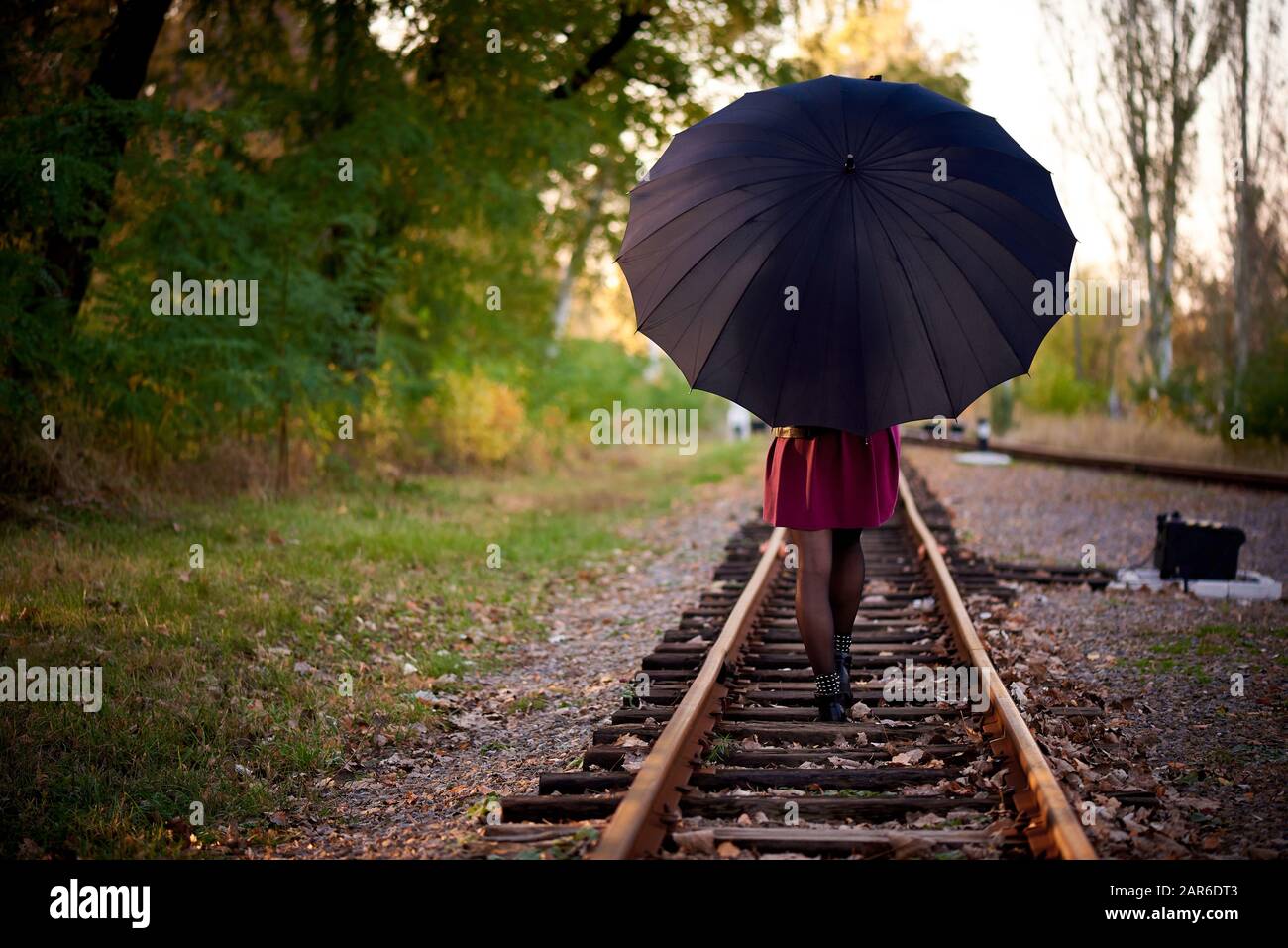 Ein Mädchen mit schwarzem Regenschirm läuft auf der Bahn. Stockfoto