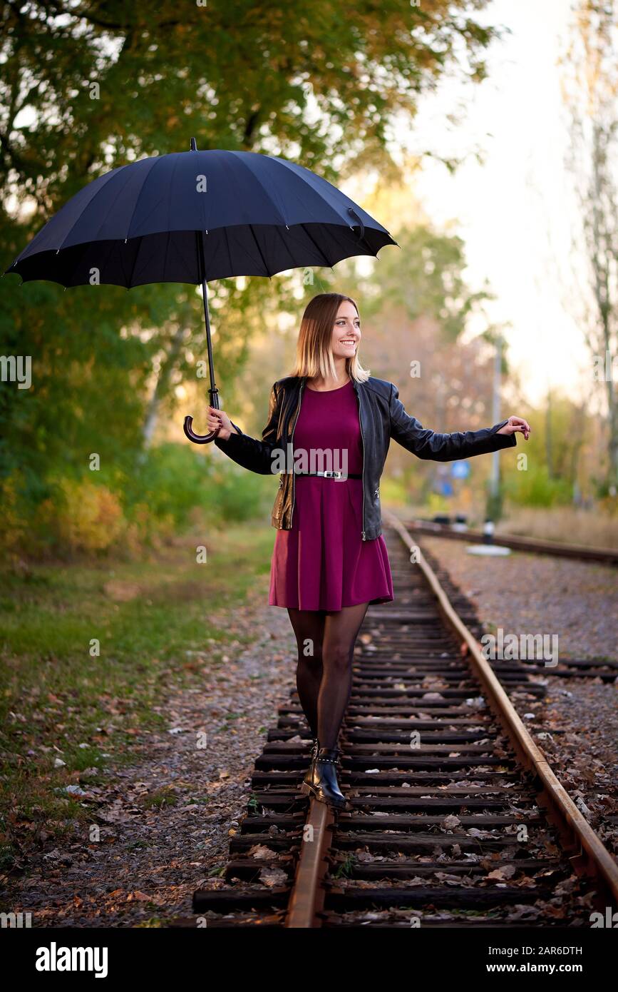 Ein Mädchen mit schwarzem Regenschirm läuft auf der Bahn. Stockfoto
