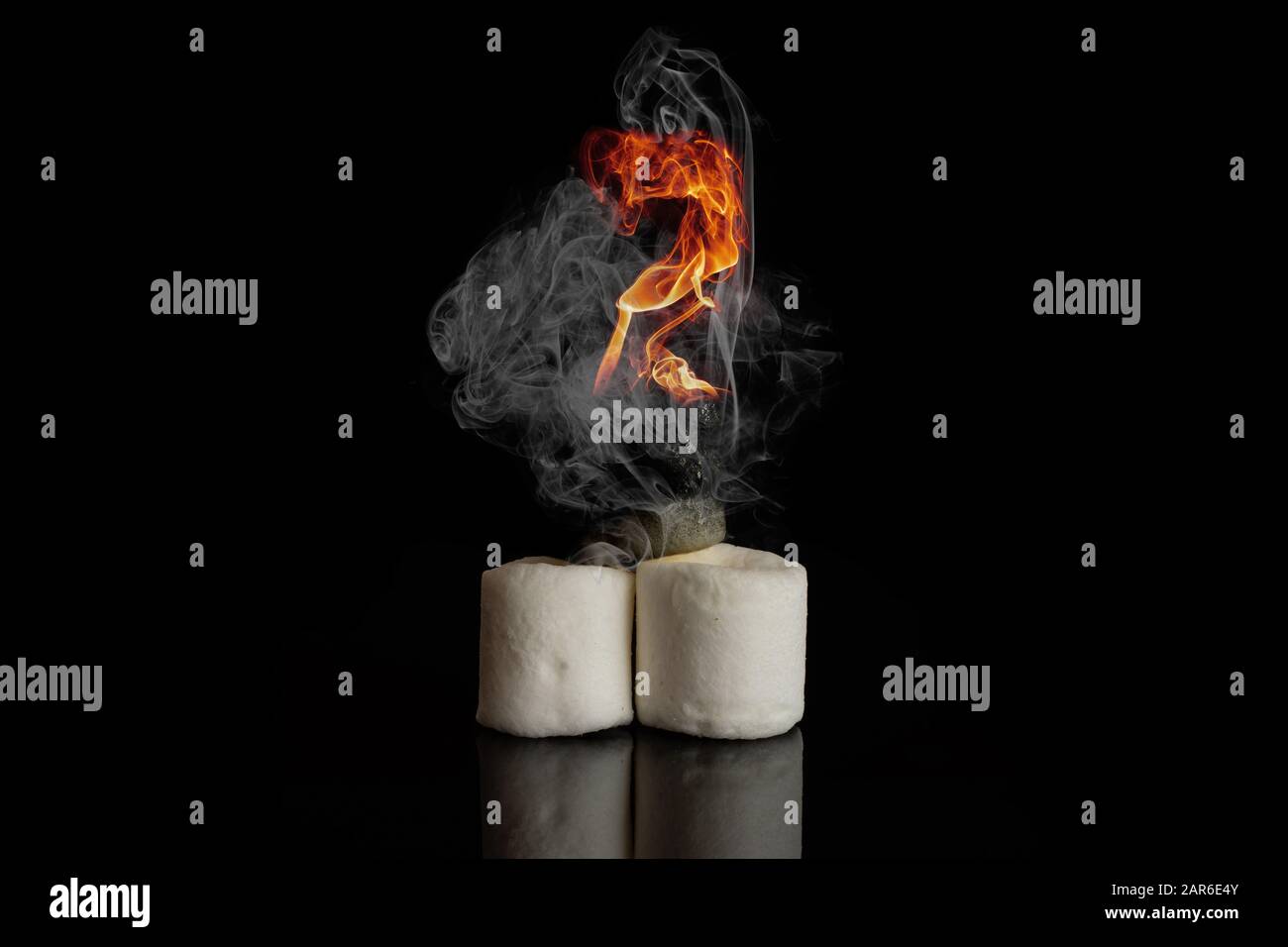 Drei süße Marshmallow Süßigkeiten bei brennendem Brandrauch isoliert auf schwarzem Glas Stockfoto