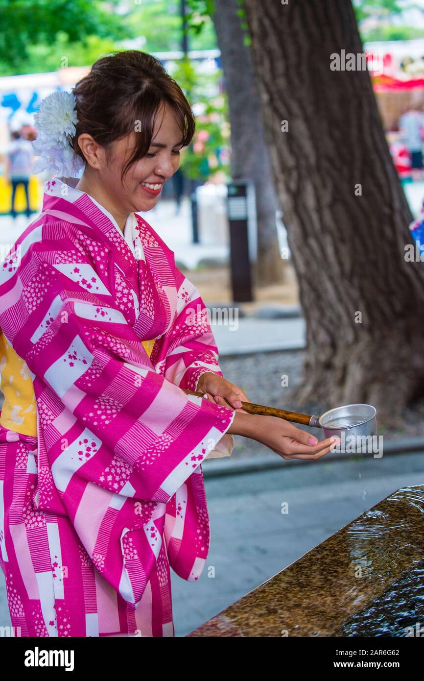 Japanische Frau, die sich in einem Schrein in Tokio Japan in einem Chozuya die Hände wäscht Stockfoto