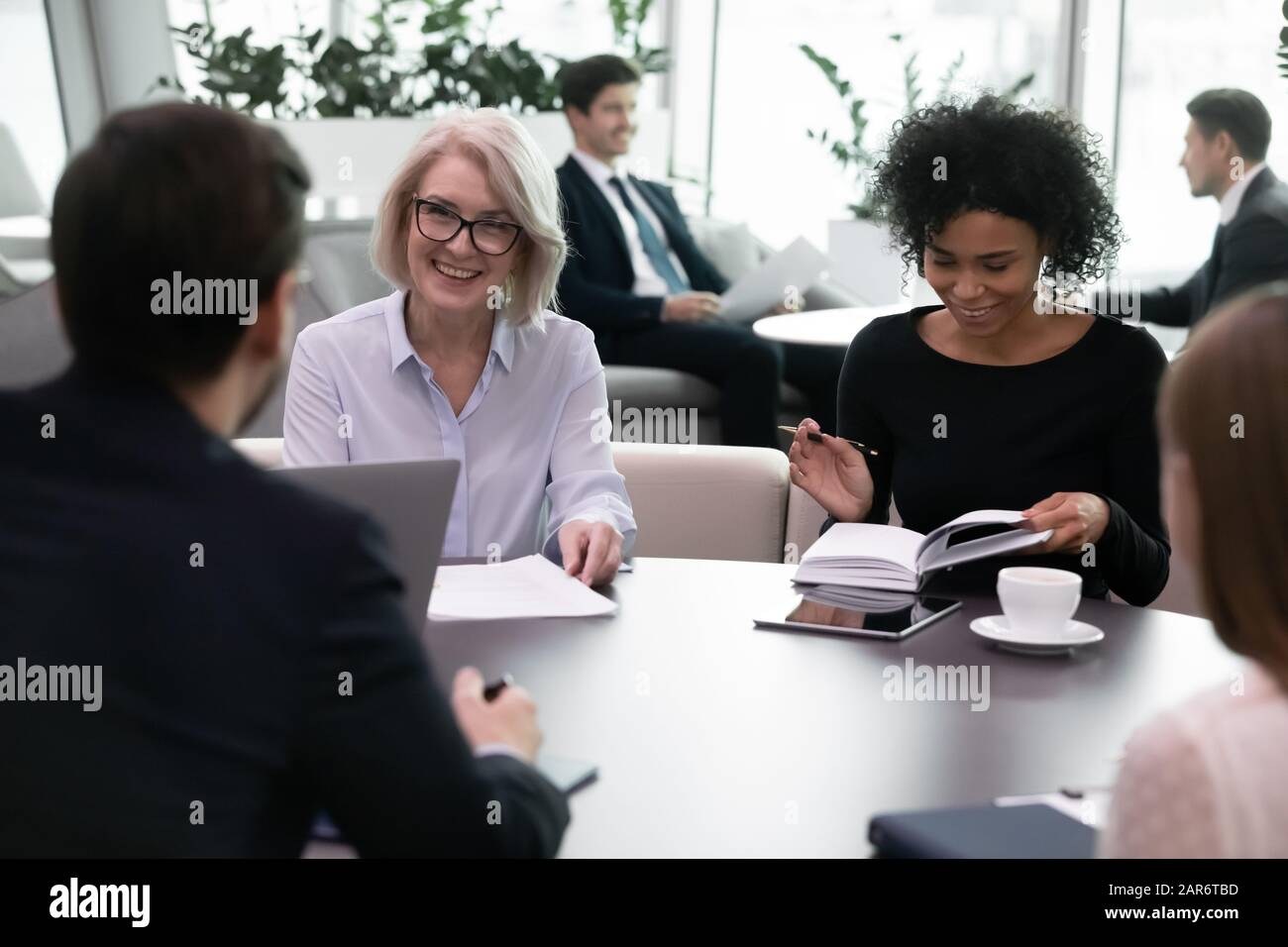 Lächelnde, unterschiedliche Altersgruppen, multirassische Geschäftsleute treffen sich im modernen Büro. Stockfoto