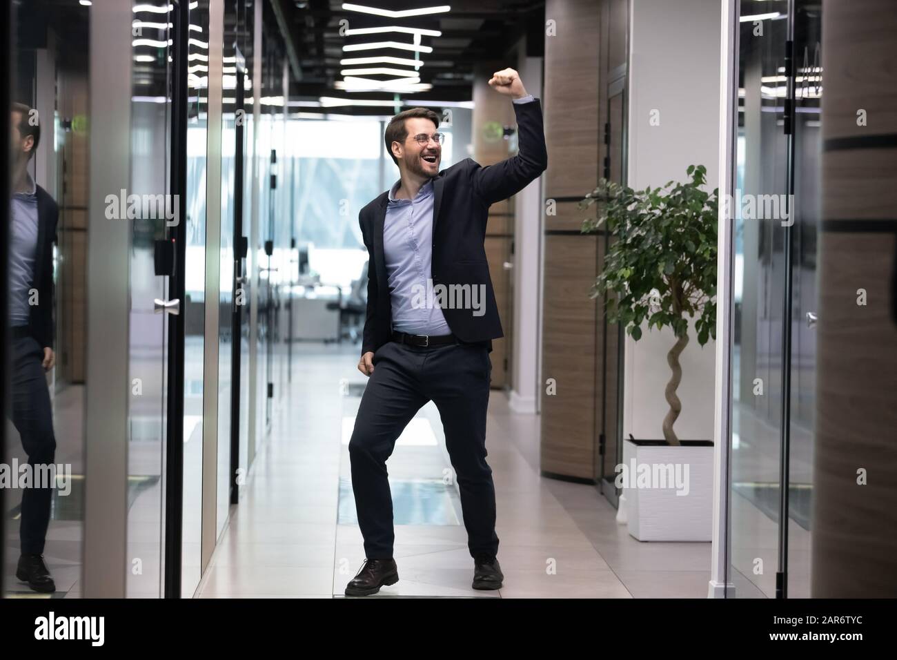 Überfreudiger junger Geschäftsmann in Anzug, der die Jobförderung feiert. Stockfoto