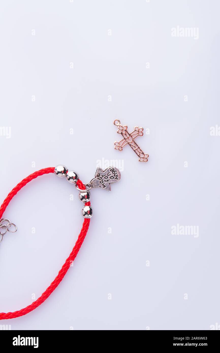 Religionsattribute, rotes Armband und goldenes Kreuz. Stockfoto