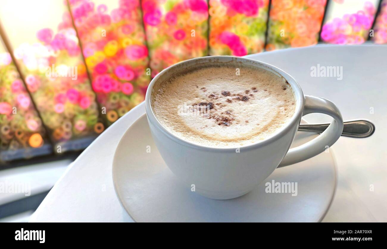 Cappuccino-Kaffee wird auf einem weißen Tisch in einem Café serviert Stockfoto