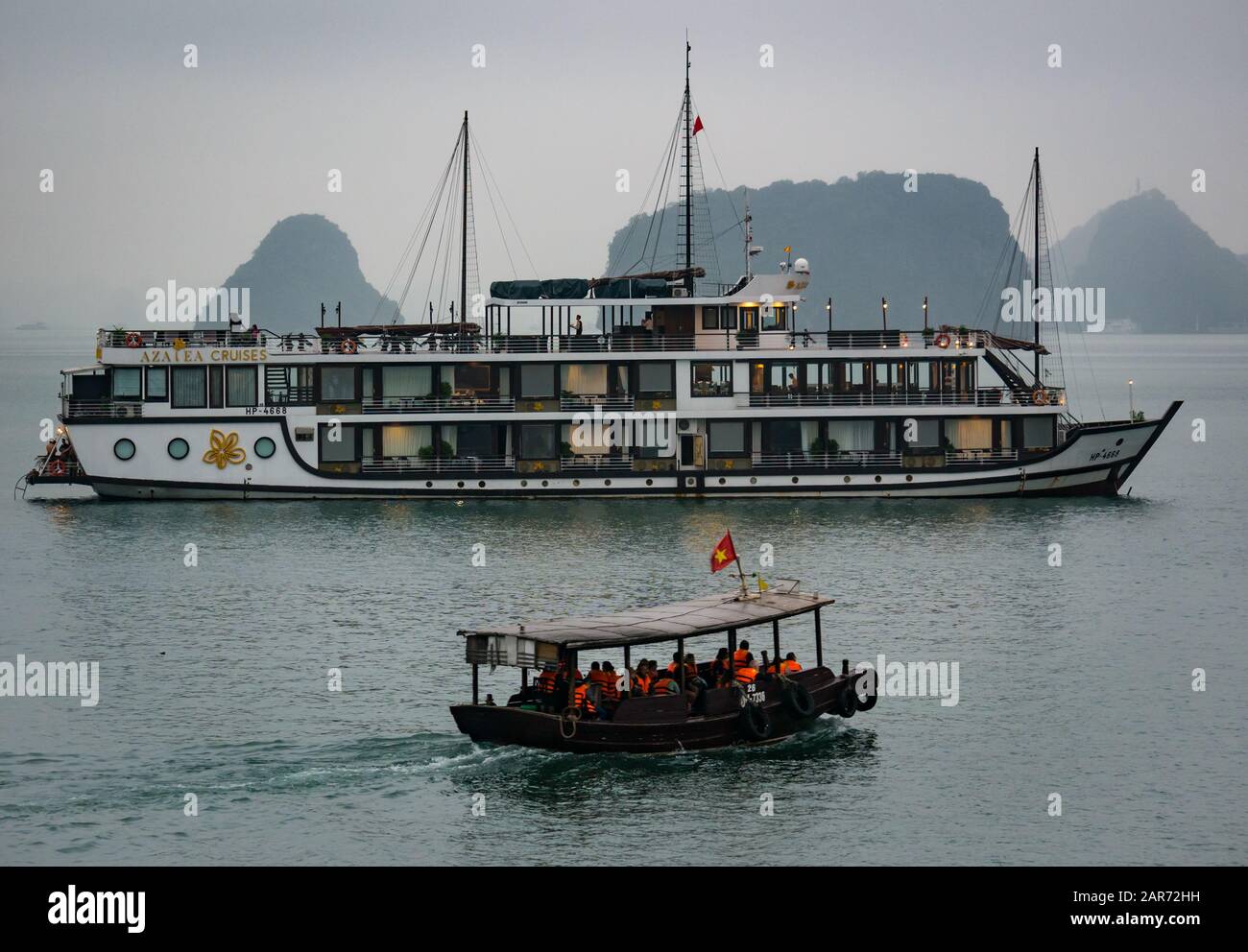 Touristen in Tender mit Kreuzfahrtschiff in Nebel in der Dämmerung, Halong Bay, Vietnam, Asien Stockfoto
